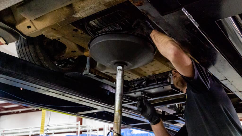 Image of oil change service being performed by a technician.